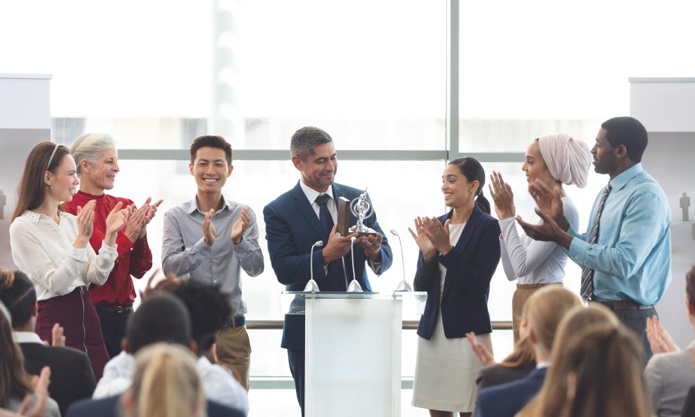 businessman-holding-award-on-podium-with-colleagues-at-business-seminar.jpg businessman-holding-award-on-podium-with-colleagues-at-business-seminar.jpg